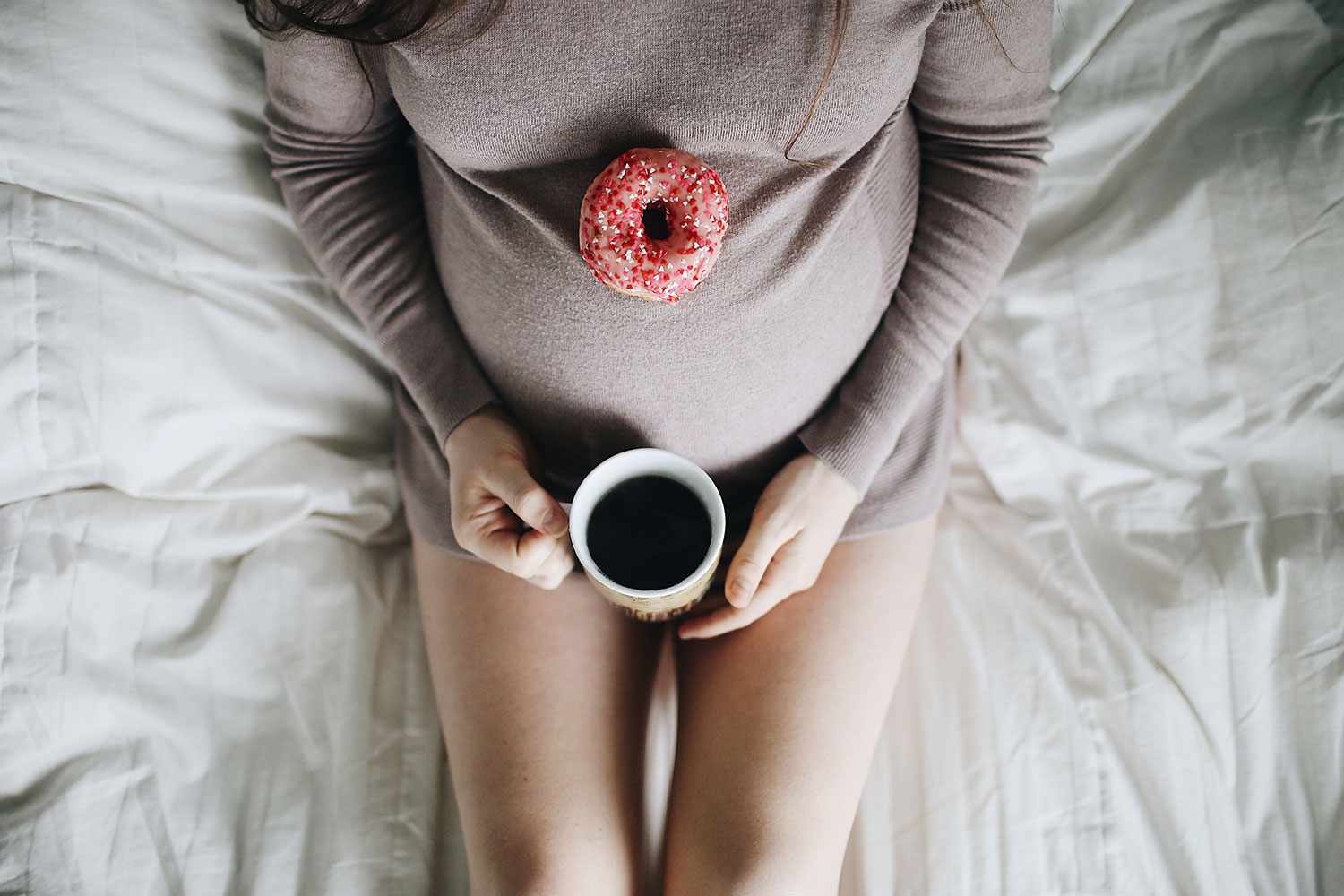 Беременная женщина с пончиком и кофе