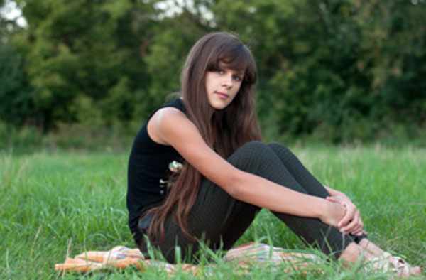 Девочка - подросток сидит на траве