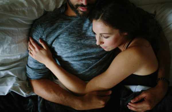 Девушка обнимает парня в постеле
